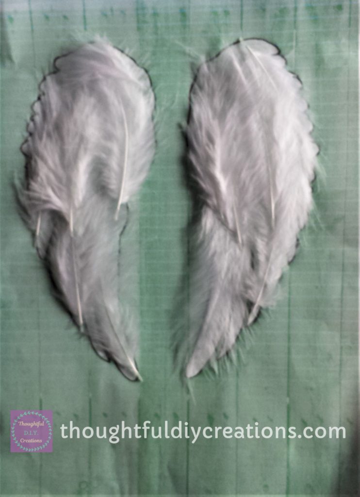 Practicing the layout of the feathers on the print-out of the angel wing silhouette before I stuck them to the canvas.