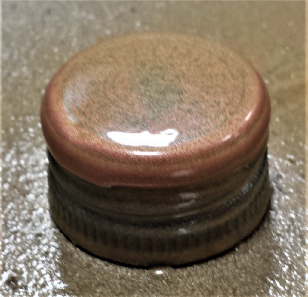 First layer of gold spray paint on the lid of the wine bottle.