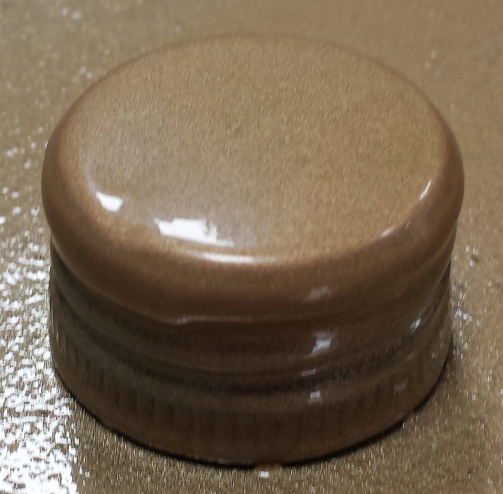 Second layer of gold spray paint on the lid of the wine bottle.