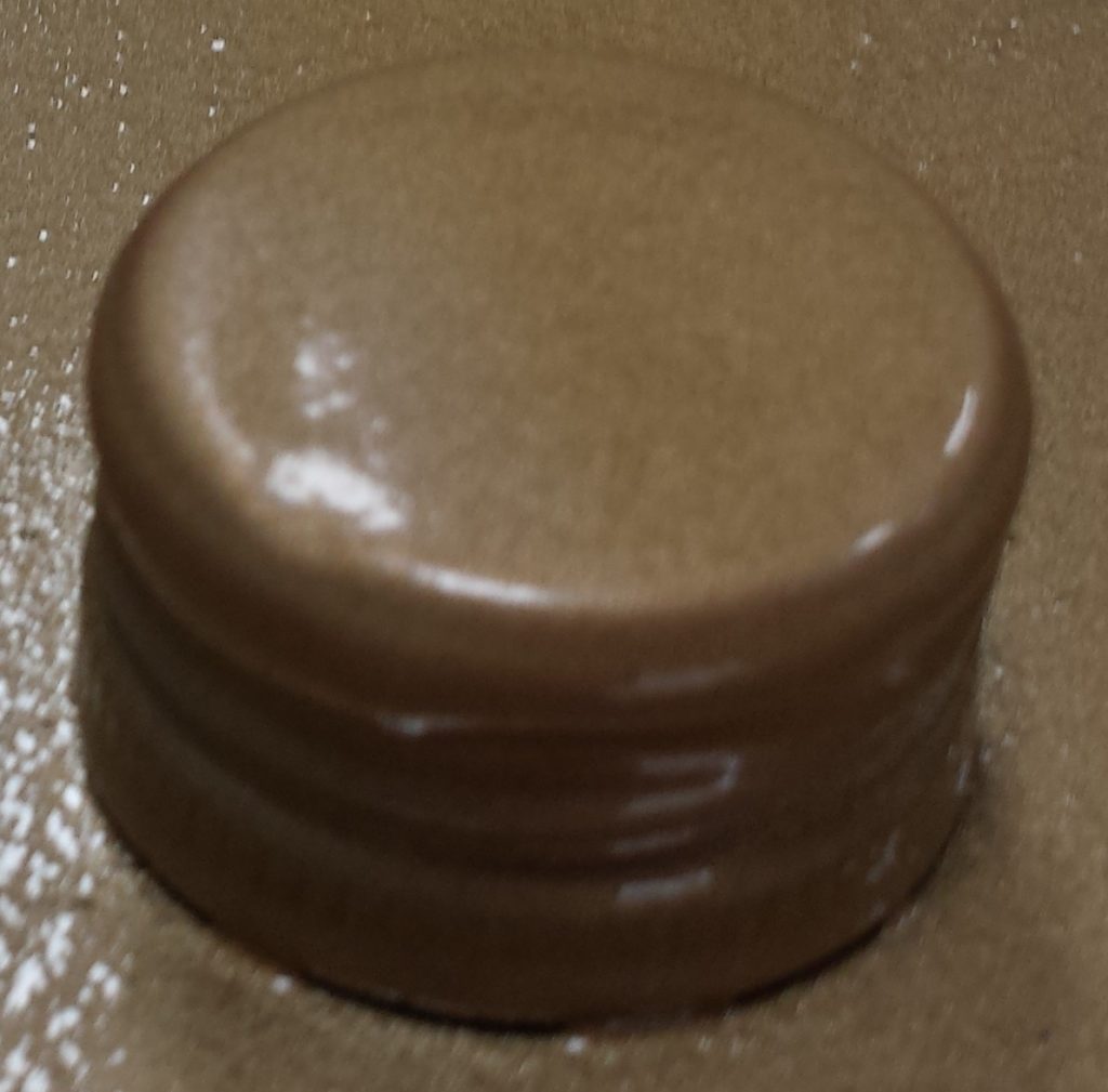 Third layer of gold spray paint on the lid of the wine bottle.