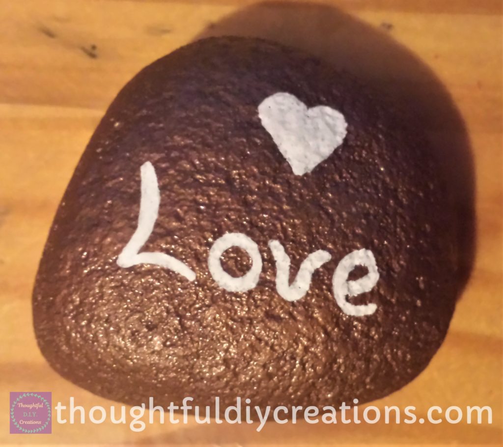 Copper Spray Painted Stone with 'Love' Sentiment wrote with a white paint pen.