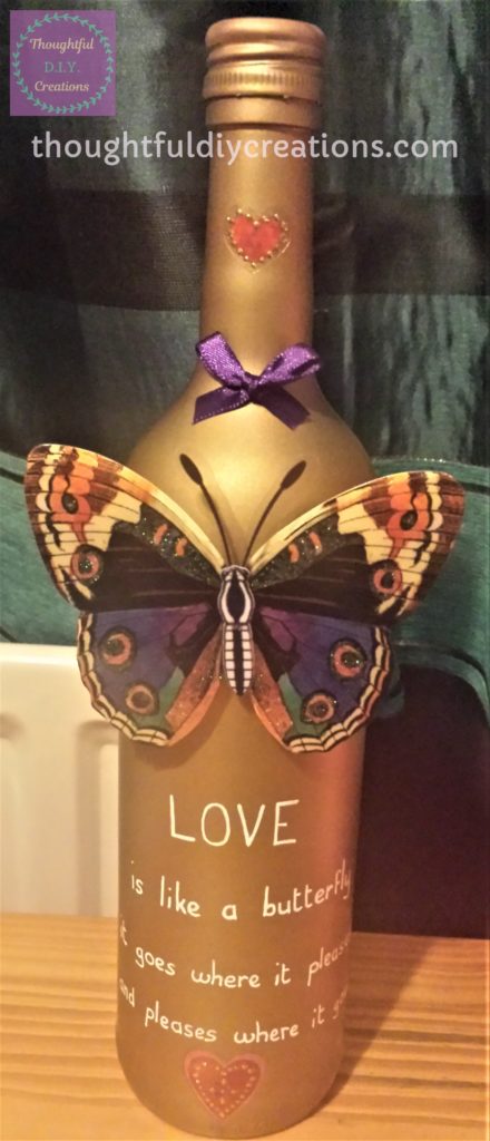 Final Photograph of Gold Spray Painted Wine Bottle with Love Quote, decorated with bow and stickers.