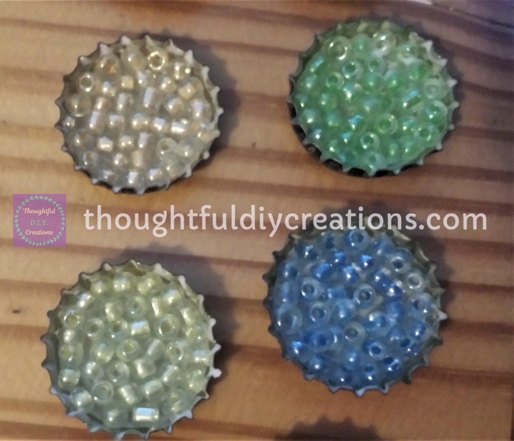 4 Beer Bottle Caps filled with beads.