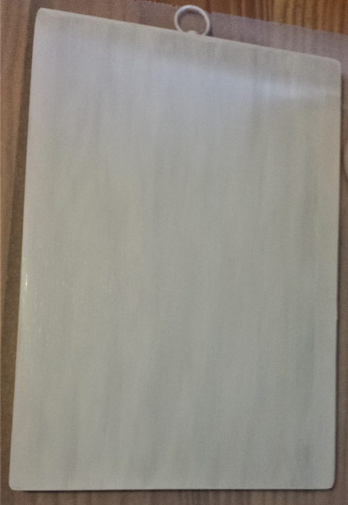 First layer of white paint on the front of the chopping board.