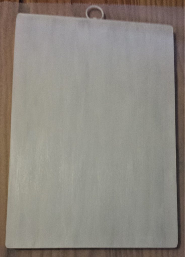 Second layer of white paint on the front of the chopping board.