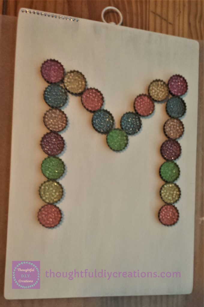 Monogram of Bottle Cap Beads hot glued to the chopping board.