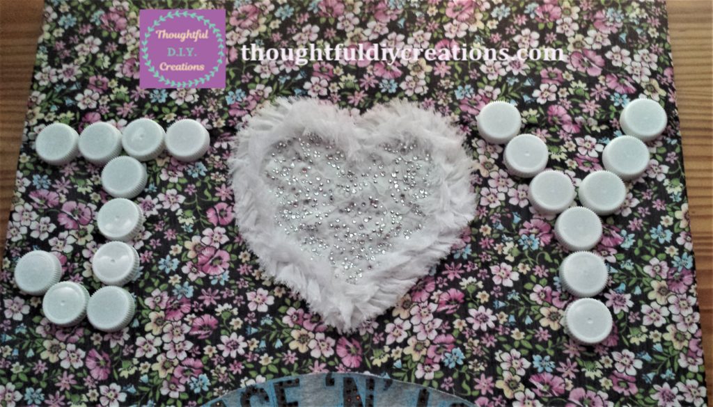 Planning the layout of the word JOY on the floral fabric canvas.