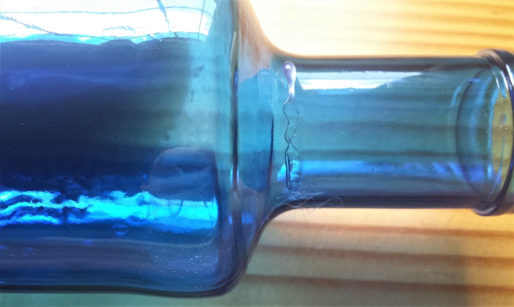 A strip of hot glue on the bottom of the neck at the back of the bottle.