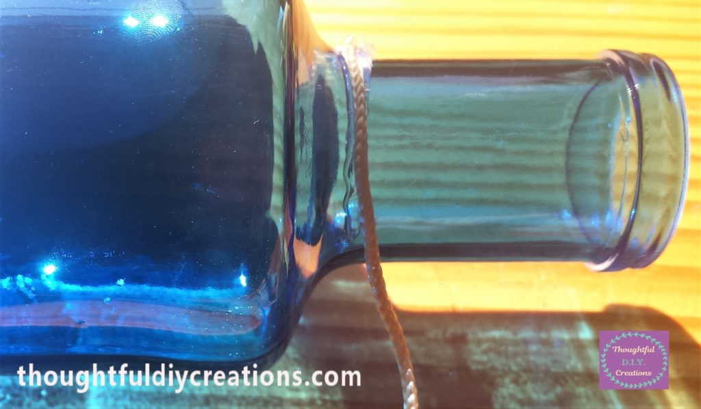 String attached to the hot glue at the bottom of the neck of the bottle.