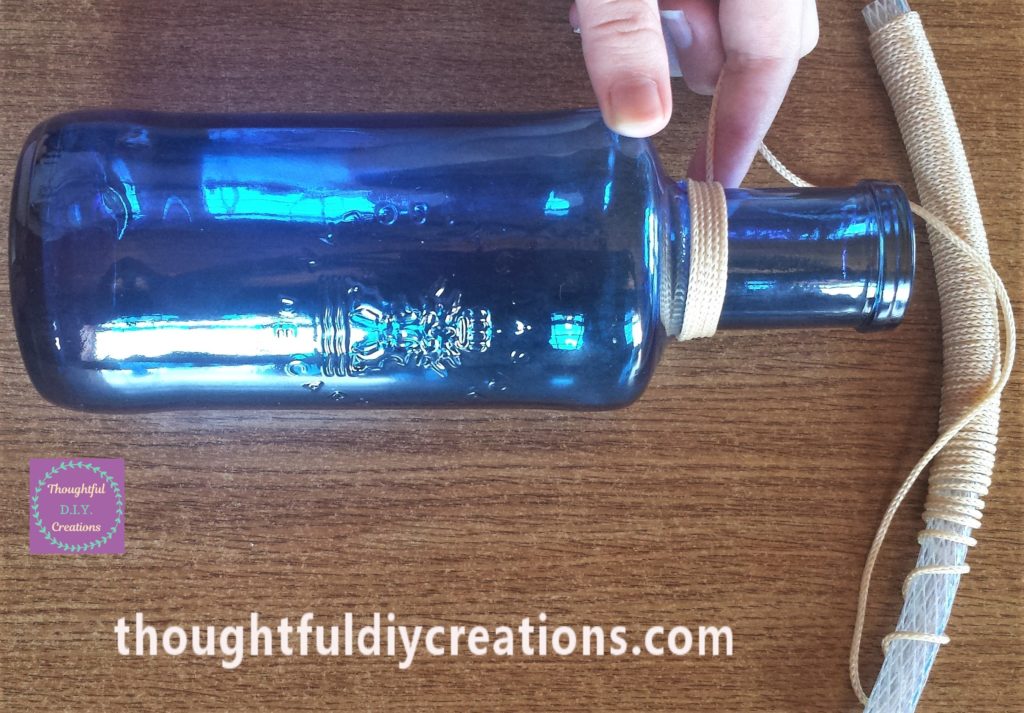 Adding the string around the neck of the bottle.