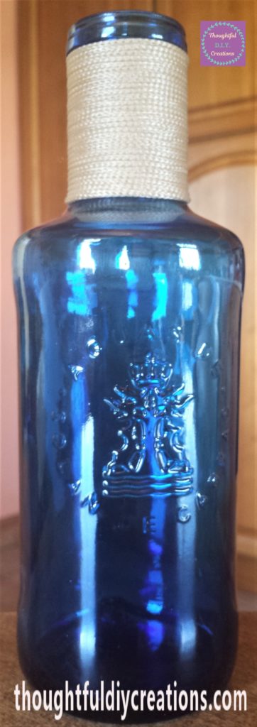 The bottle standing up, the front view of the neck of the bottle filled with string.