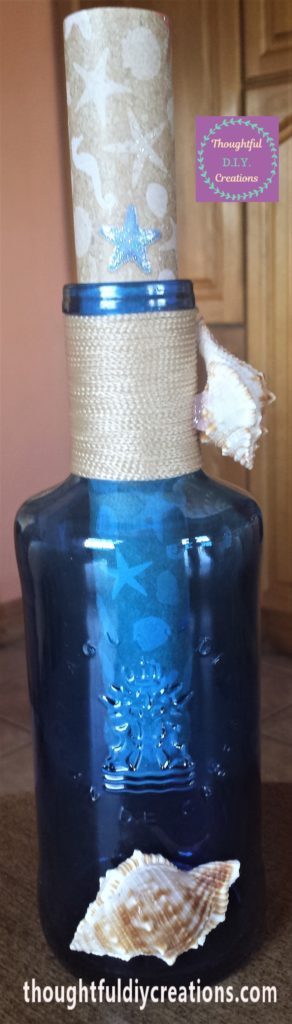 The bigger shell hot glued to the front of the bottle near the bottom.