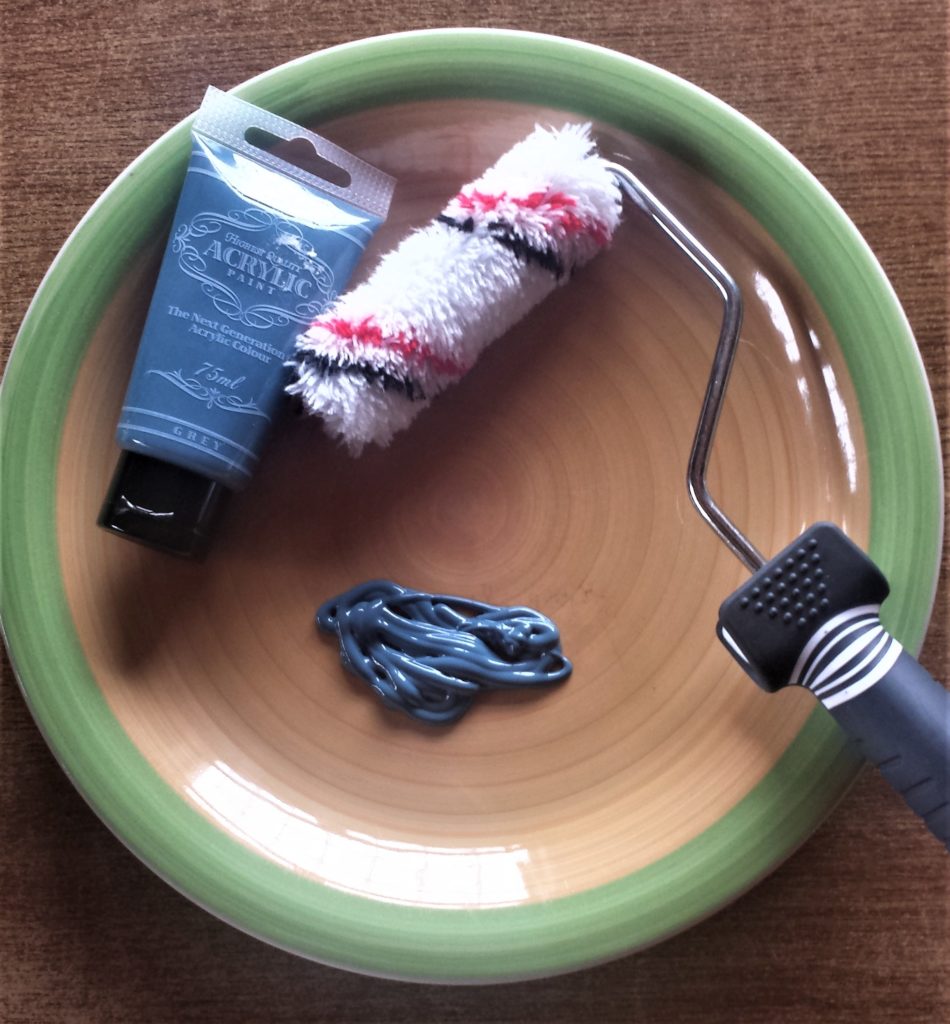 Paint poured onto an old plate. The roller is on the plate.