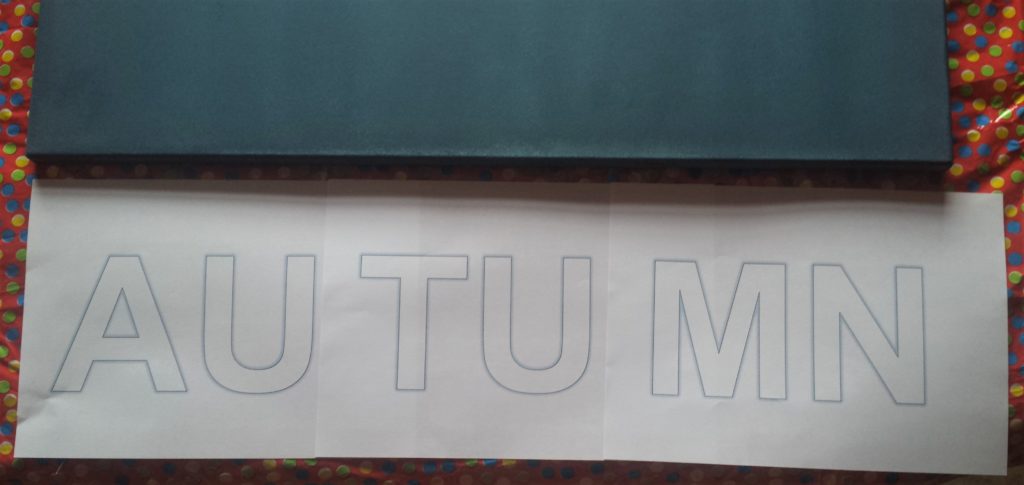 The word AUTUMN printed out on three pages, two letters on each page.