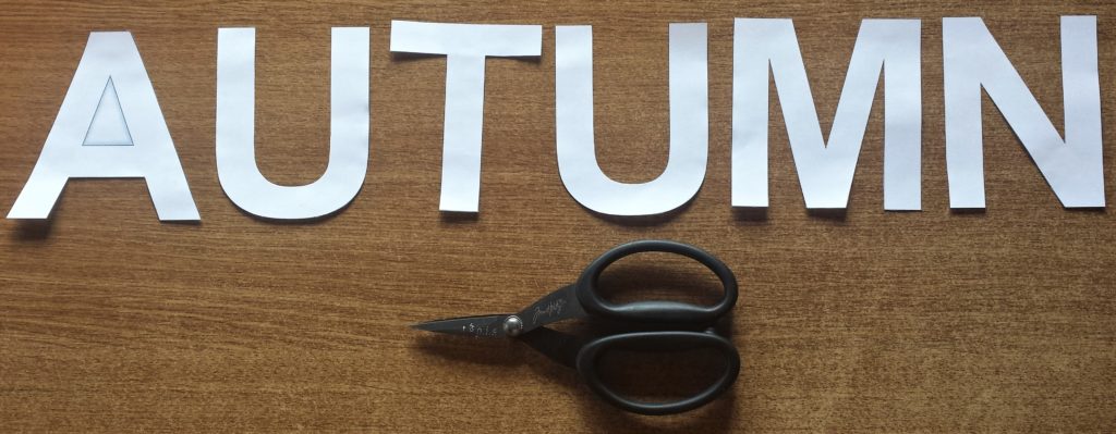 Cutting out the letters to spell Autumn with a Tim Holtz Scissors.
