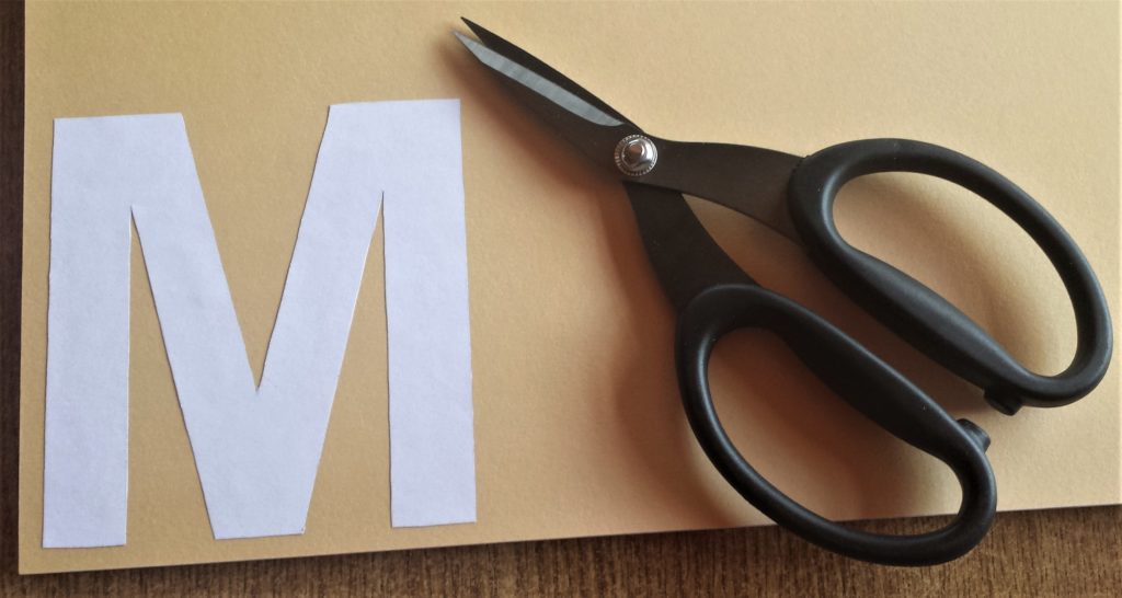 The letter 'M' glued to the Autumn paper.