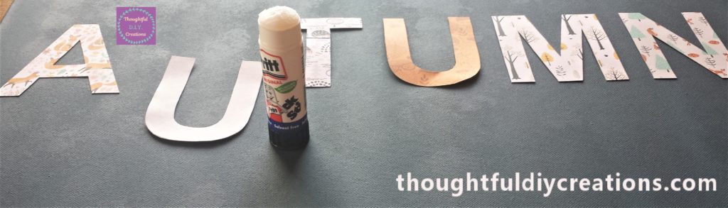 Gluing the Autumn letters to the Canvas using pritt stick.