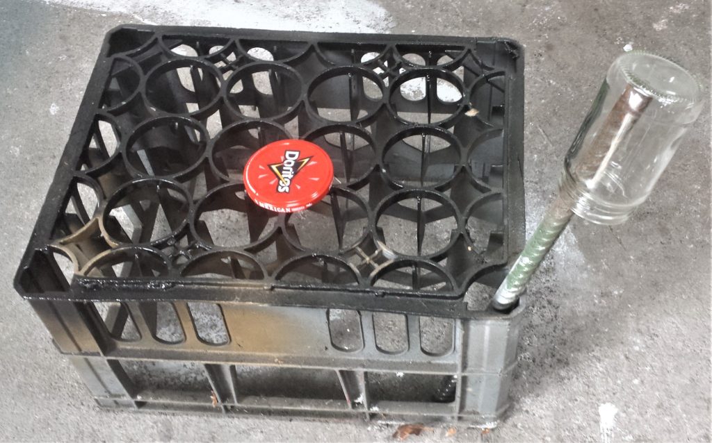Jar balancing on an iron bar in a gap in the crate. The lid is on the crate.