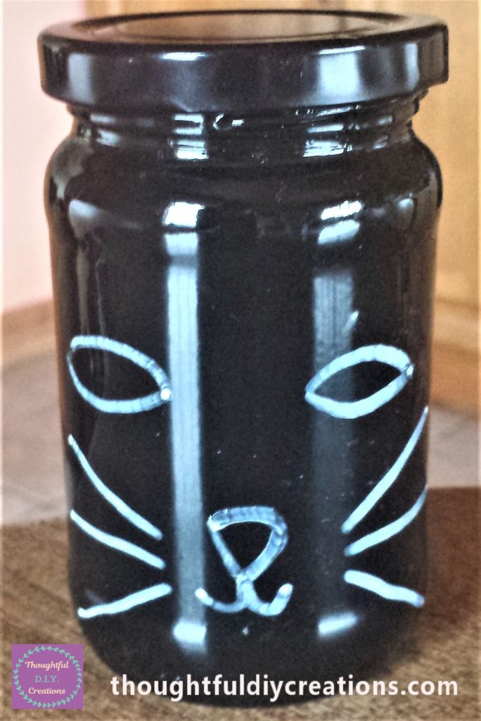 Cats face drawn on the jar with a white paint marker.