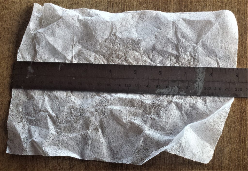 Making a mark at 6 and 1/4 inches on the tumble dryer sheet with a pencil.