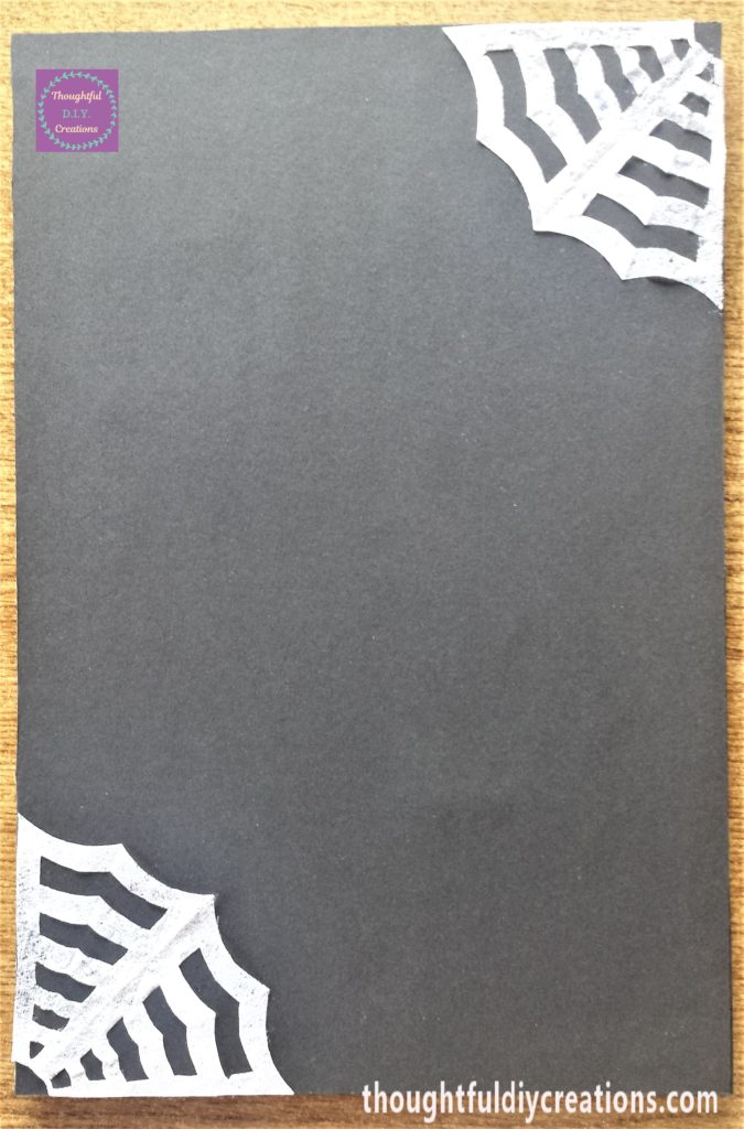 Spiderwebs attached to the top right hand corner and bottom left hand corner of the frame.