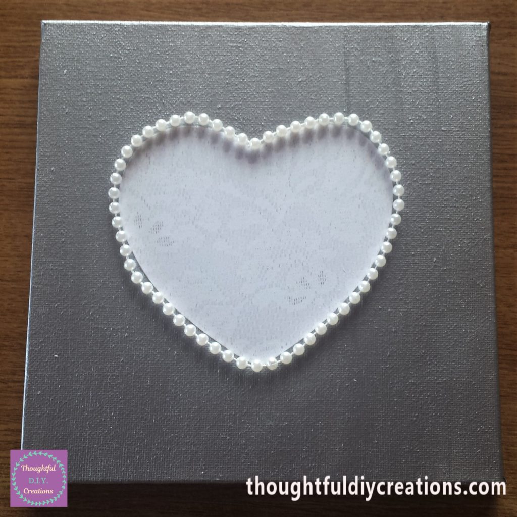 The beads glued around the heart on the canvas.