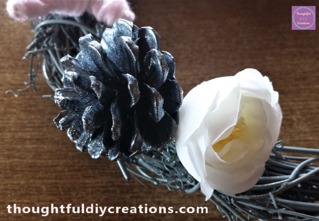 Close up image of the pine cone and flower glued to the wreath.