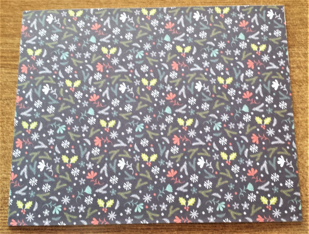 The Christmas paper smoothed onto the canvas board.