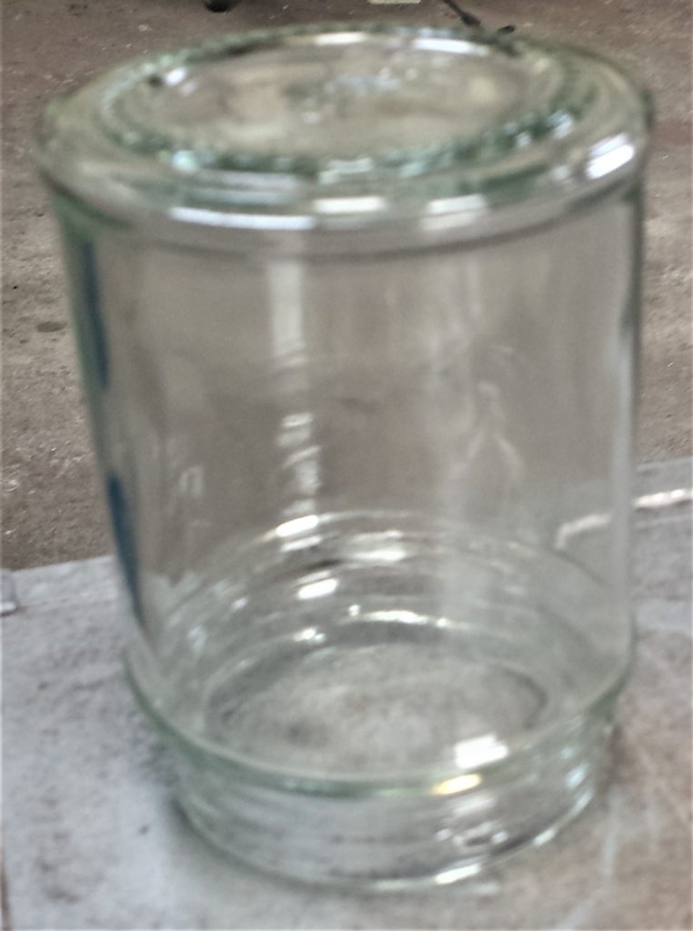 The smallest jar upside down on the table in the shed ready for spray painting.