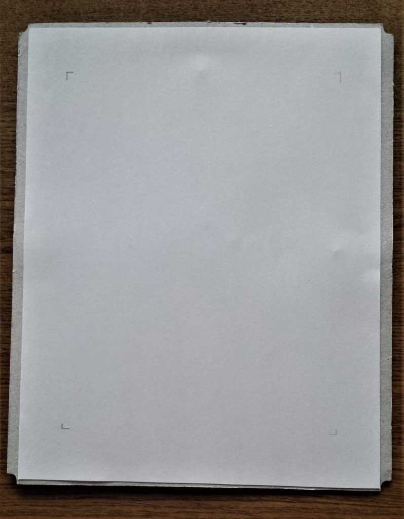 Corners marked on the white sheet attached to the backing of the frame   with a pencil to help position the blue patterned page.