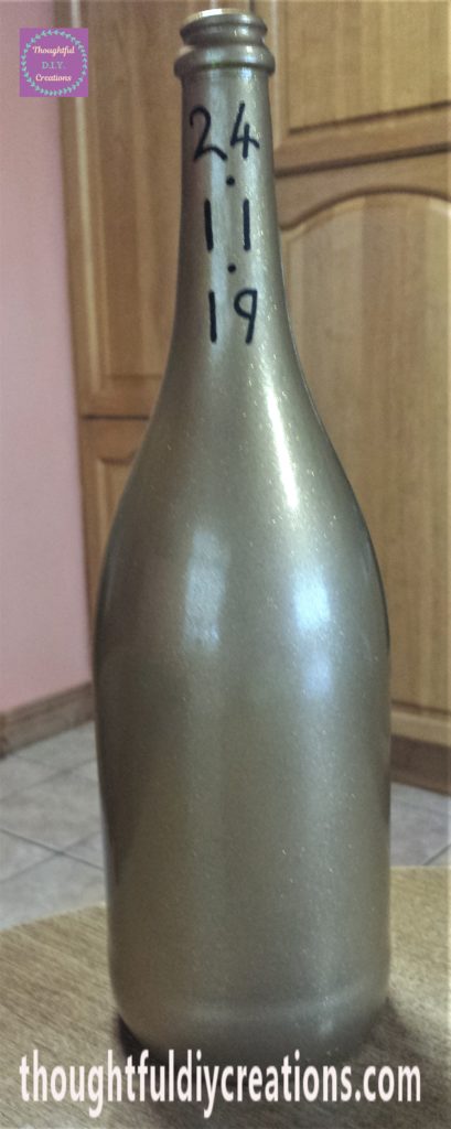 The birthday date wrote on the neck of the bottle using a paint marker.
