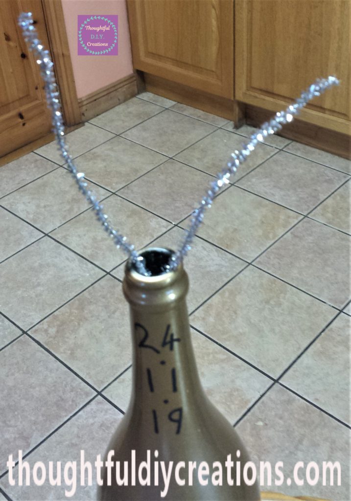 Close-up-image of the silver pipe cleaner hot glued to the inside of the bottle.