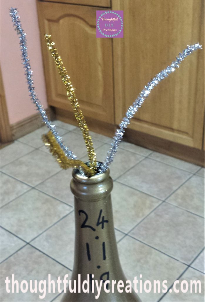 Close-up-image of the gold glitter pipe cleaner hot glued to the inside of the bottle.