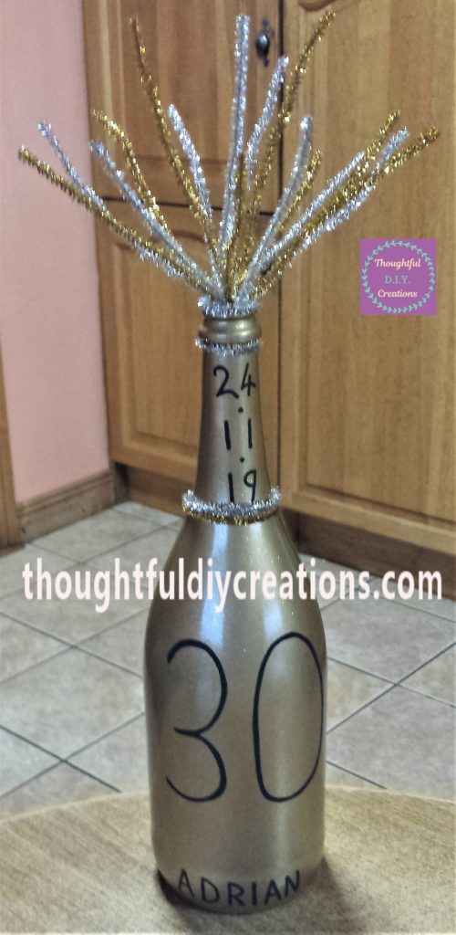 Silver and gold glittered pipe cleaner hot glued to the bottle under the date.