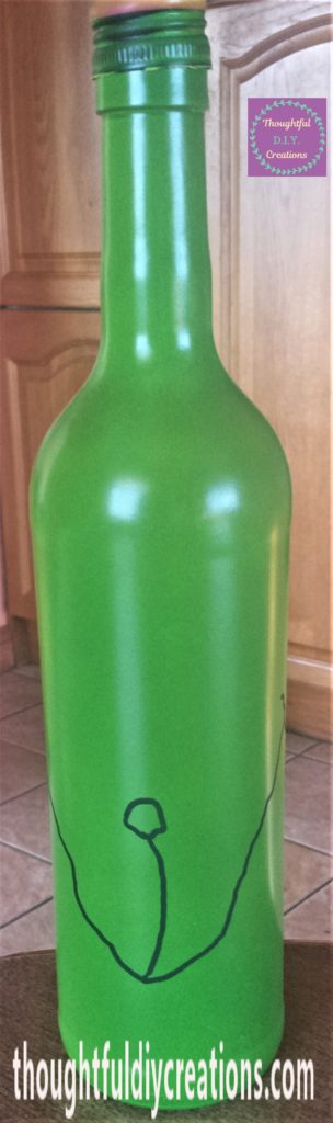 The Grinch's mouth and nose drawn onto the green bottle using the black paint marker.