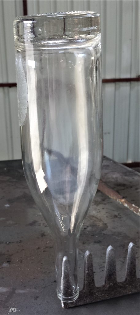 Wine Bottle balanced on a spike of a rake.