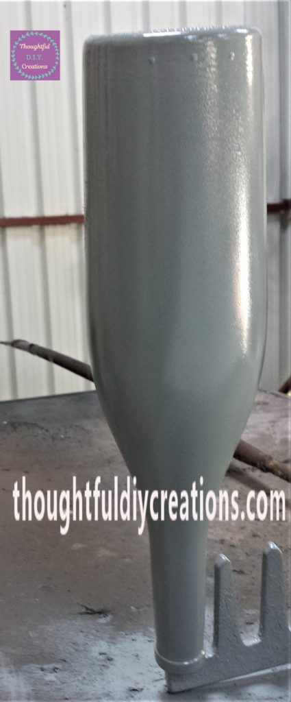 The third and final layer of spray paint applied to the wine bottle.