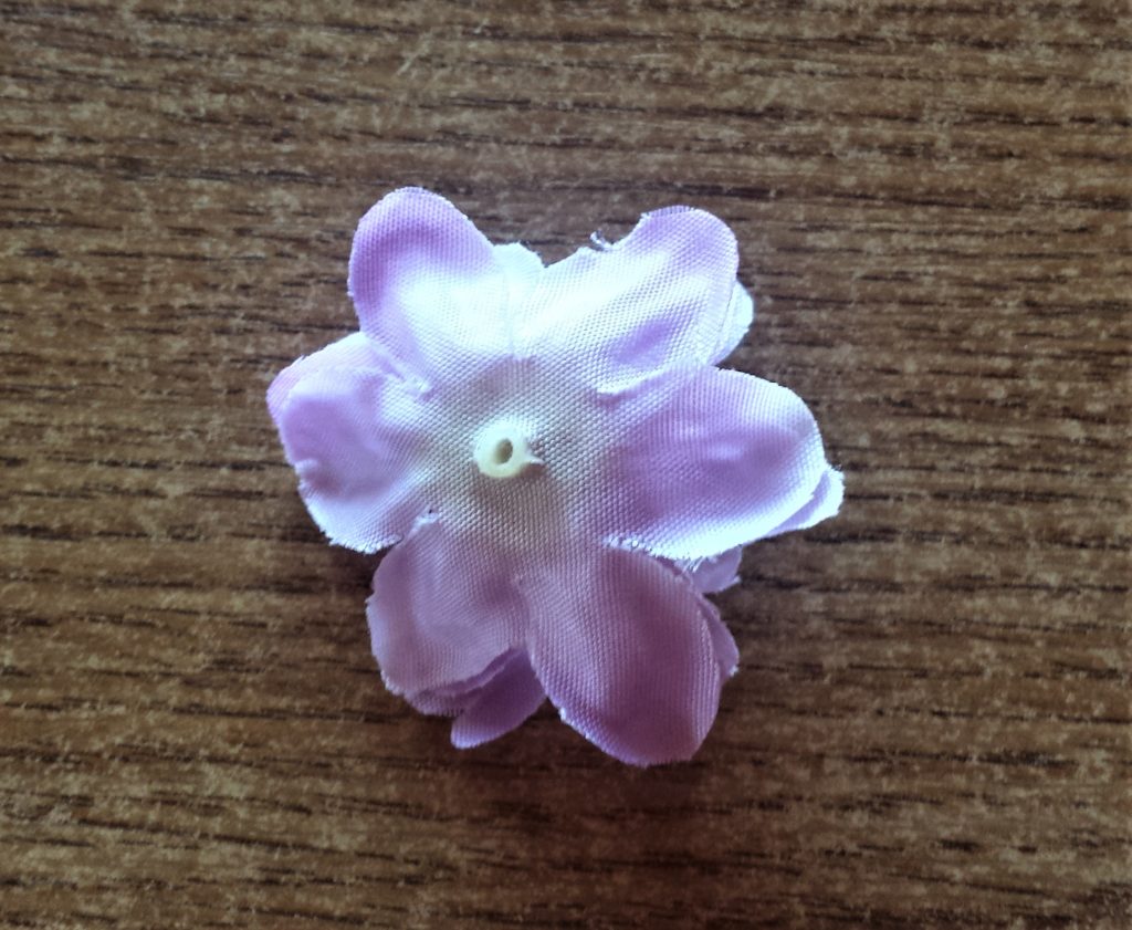 The plastic part sticking out of the back of the flower cut off using a scissors..