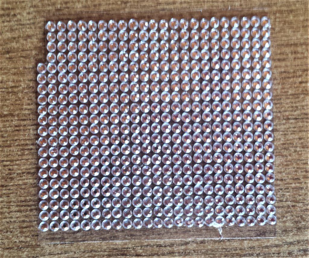 A strip of 4 gemstones cut from the clear backing sheet.