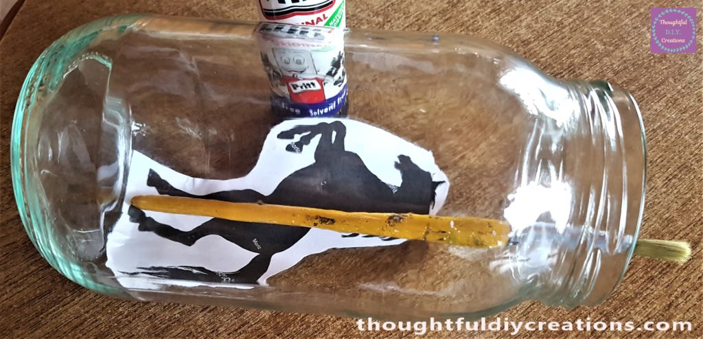 Using the handle of a paintbrush to press the image to the curves of the jar.