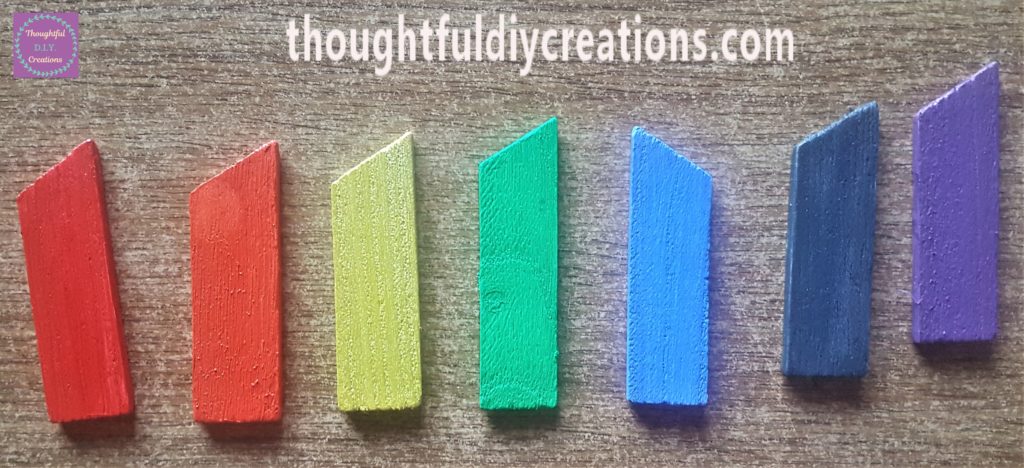 The wooden pieces painted with acrylic paint the colours of the rainbow, red, orange, yellow, green, blue, indigo and violet.