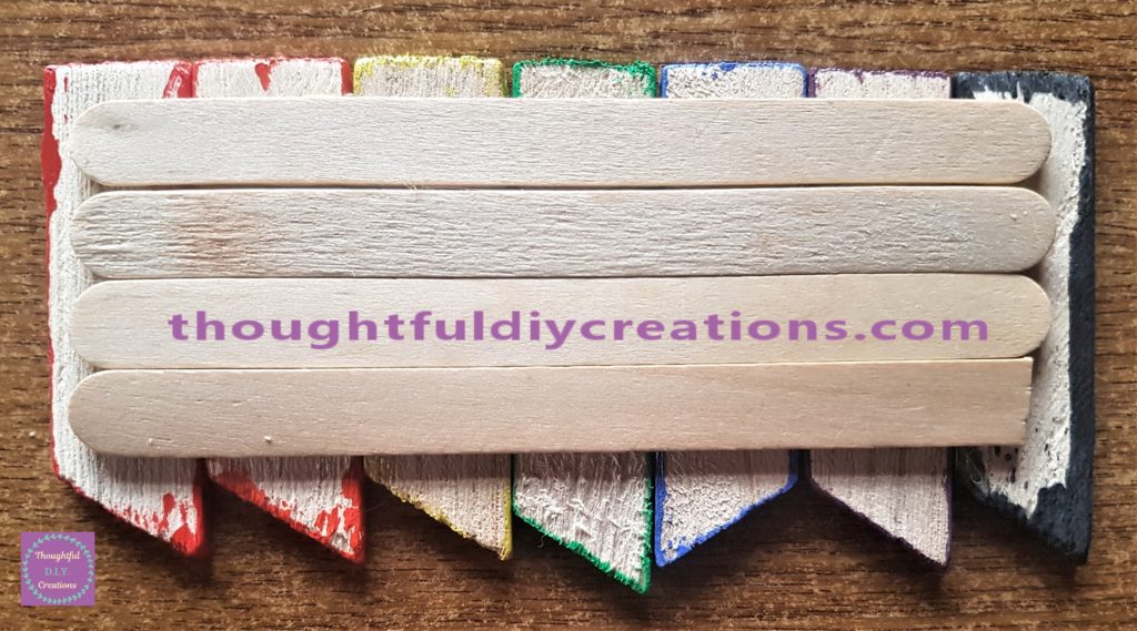 4 plain Lollipop sticks hot glued close together to the back of the rainbow path to ensure it is level when upright.