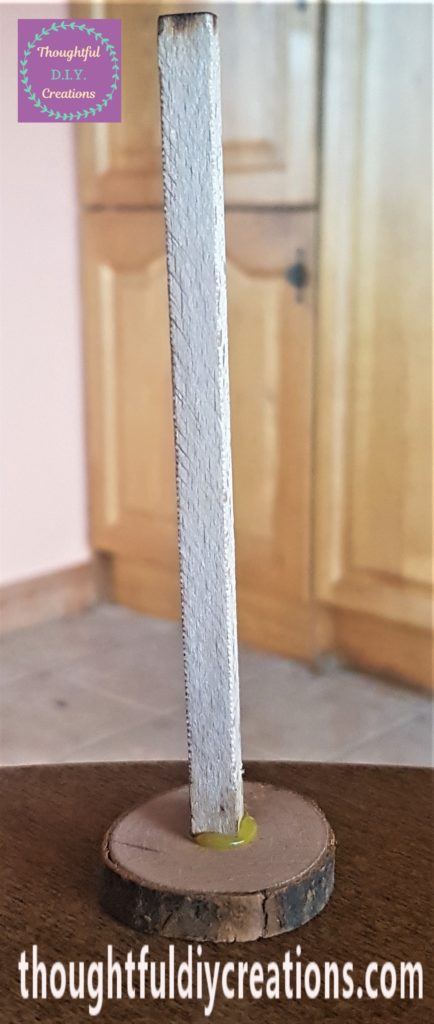 The wooden stick hot glued in the center of the wood slice.