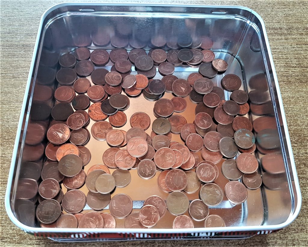 1 and 2 Cent coins in a metal container.