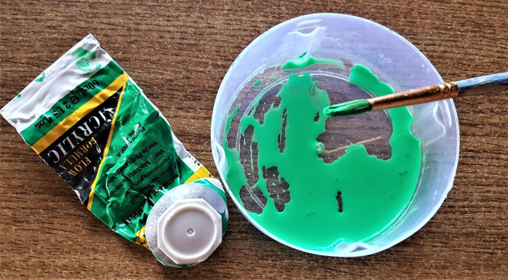 Green acrylic paint in an old lid with water added and mixed together with a paintbrush.