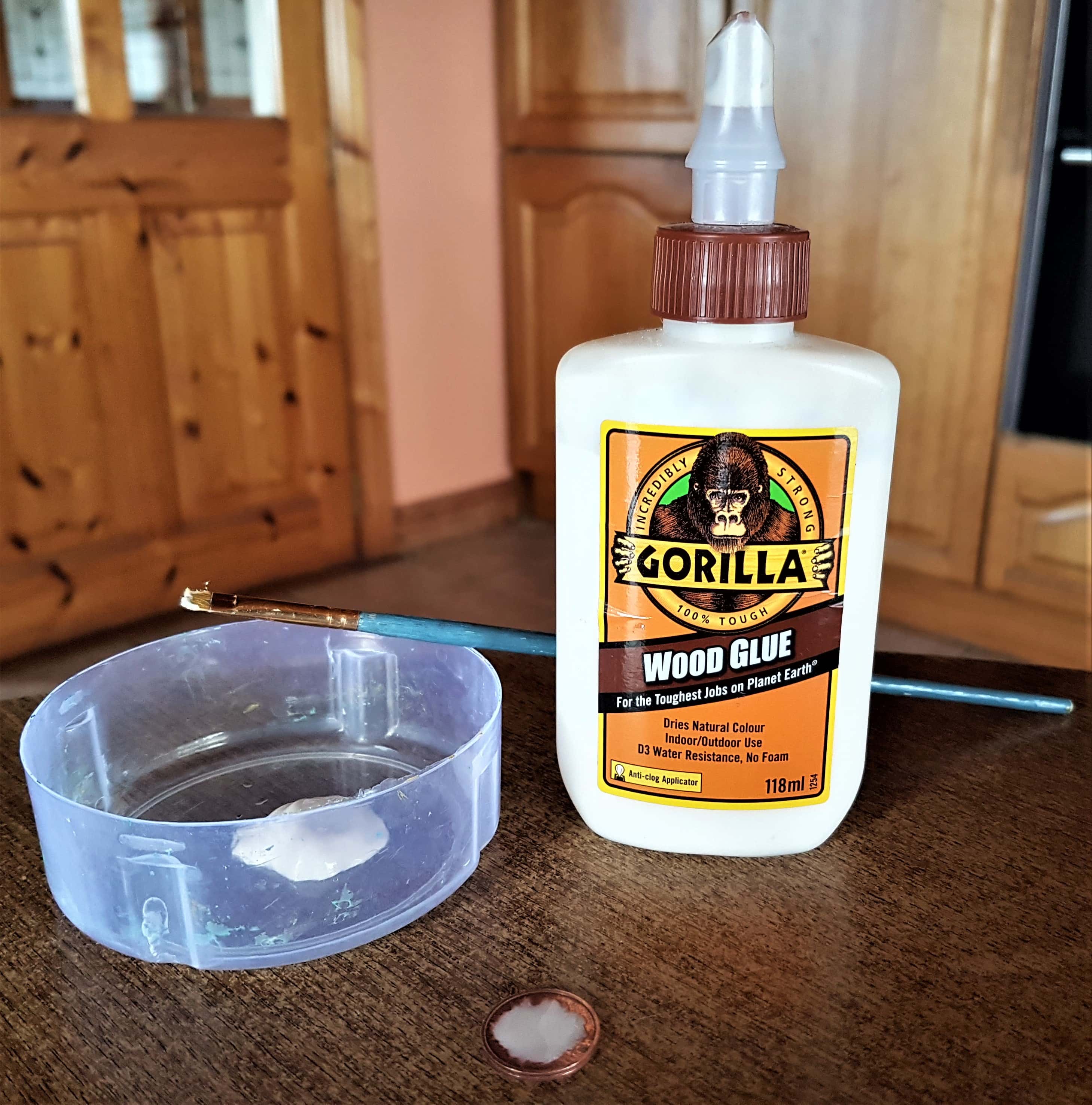 Some Gorilla Wood Glue poured into a lid. Glue put on the back of the coin with a small paintbrush.