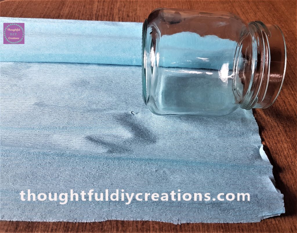 The jar face down on the blue crepe paper to get the lenght of the jar.