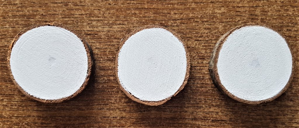 A second layer of paint added to each wood slice.