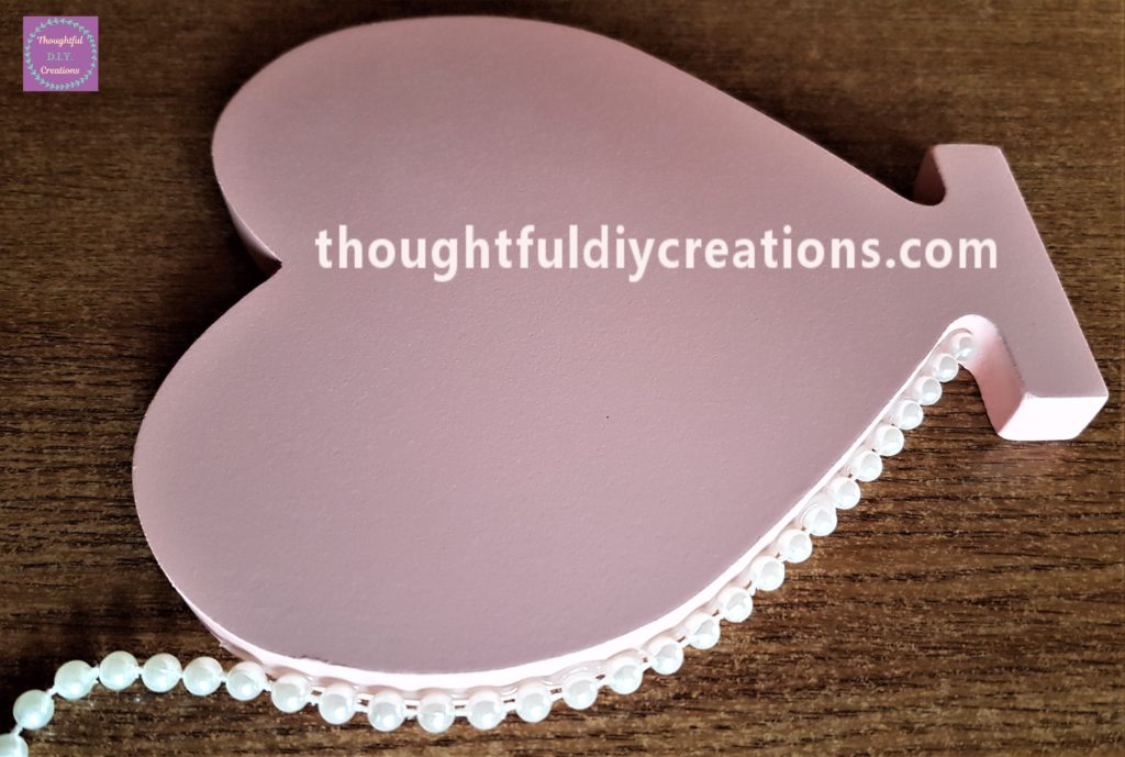 More hot glue added to the side of the heart and the pearl garland pressed into the glue.