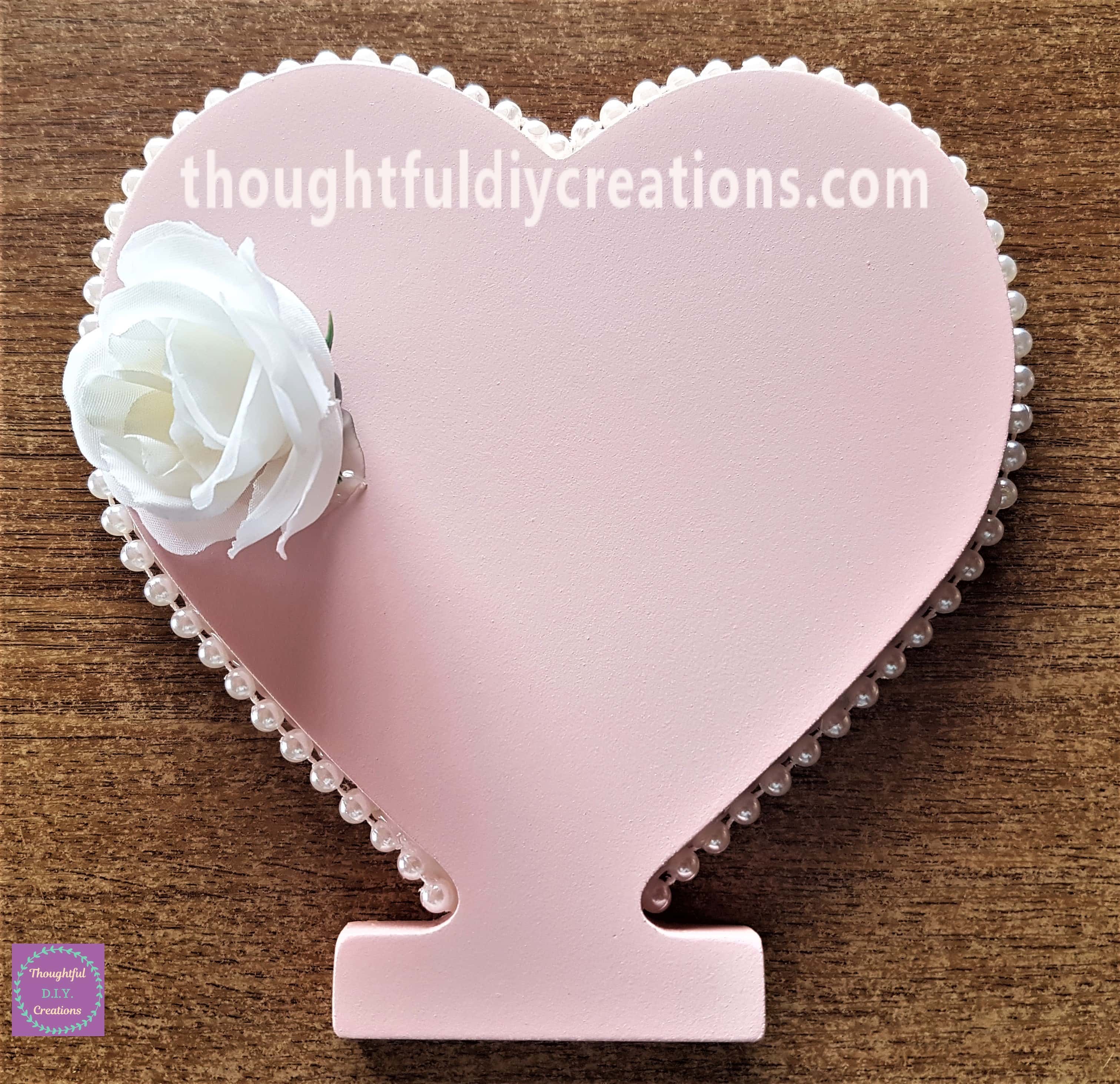 Hot glue on 1 side of the flower and attached to the pink heart.
